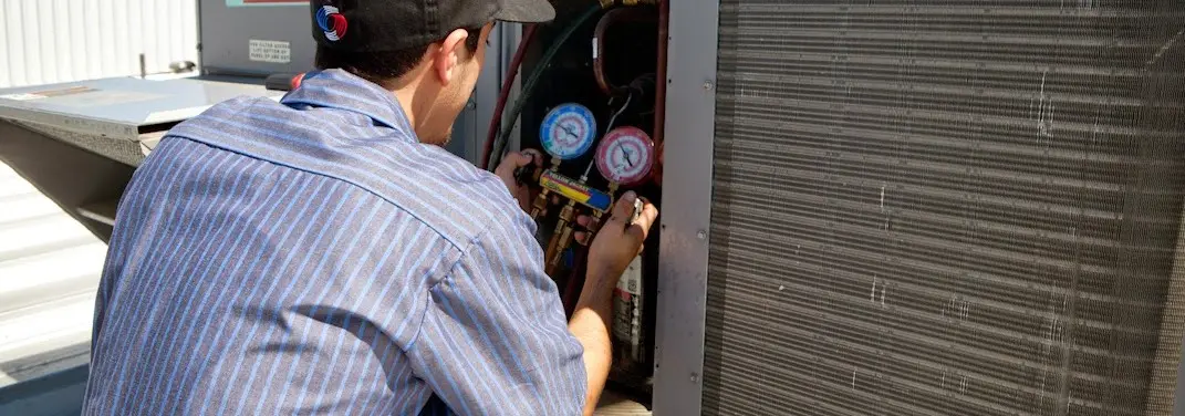 HVAC technician servicing a condenser unit in North Liberty