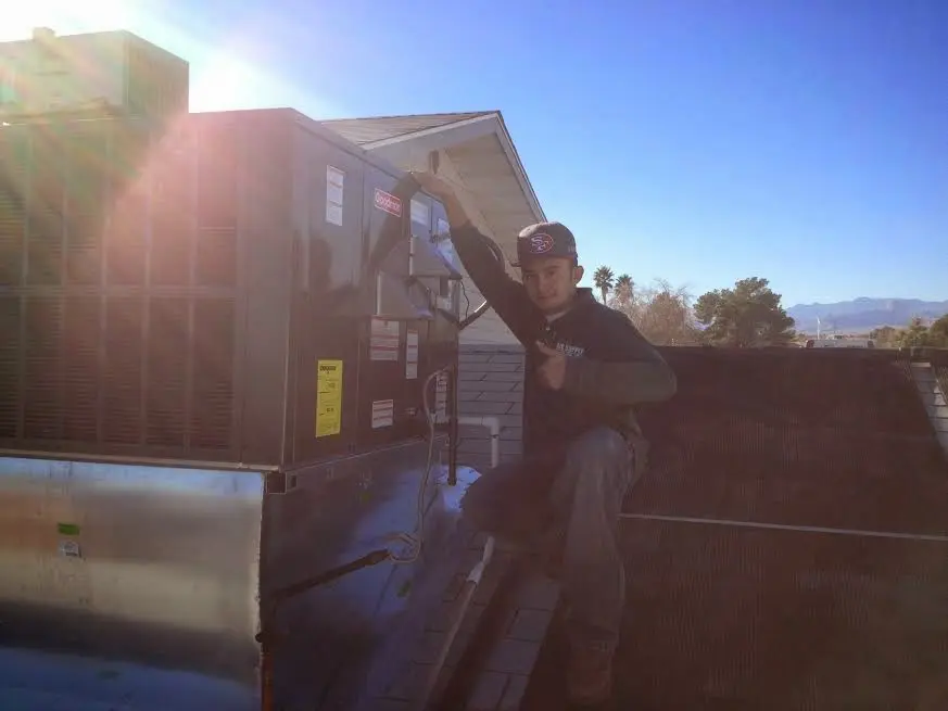 HVAC technician performing Air Duct Cleaning on a rooftop unit in North Liberty